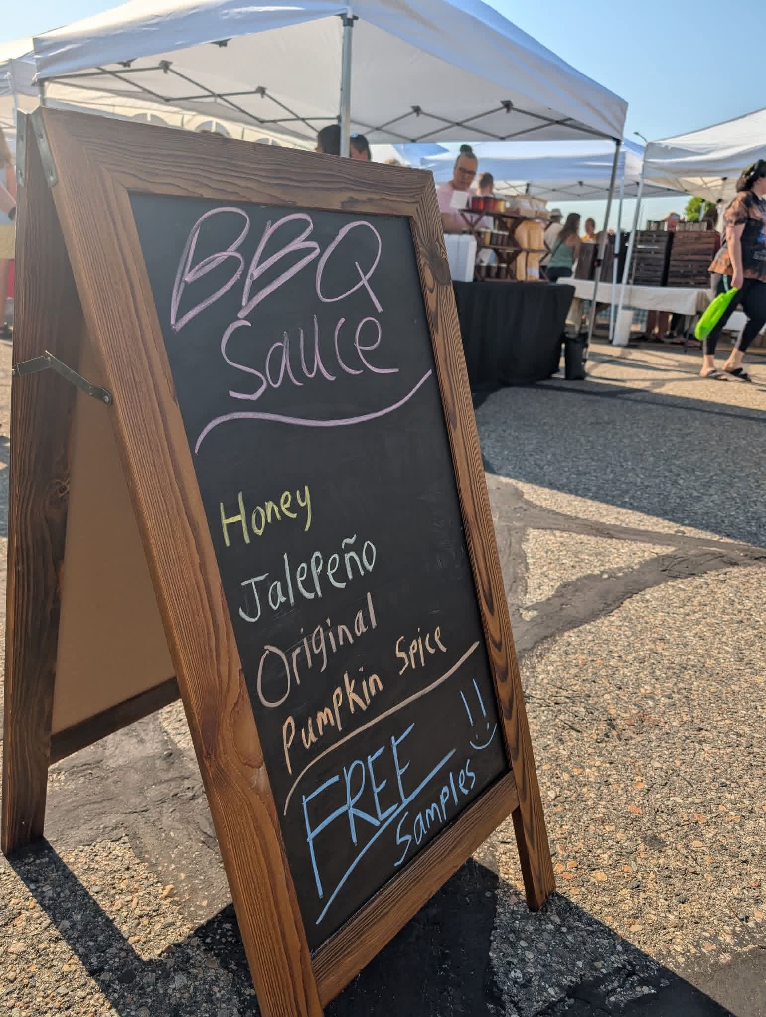 Wooden sandwich board listing Witikko Sauce Co flavors and free samples.